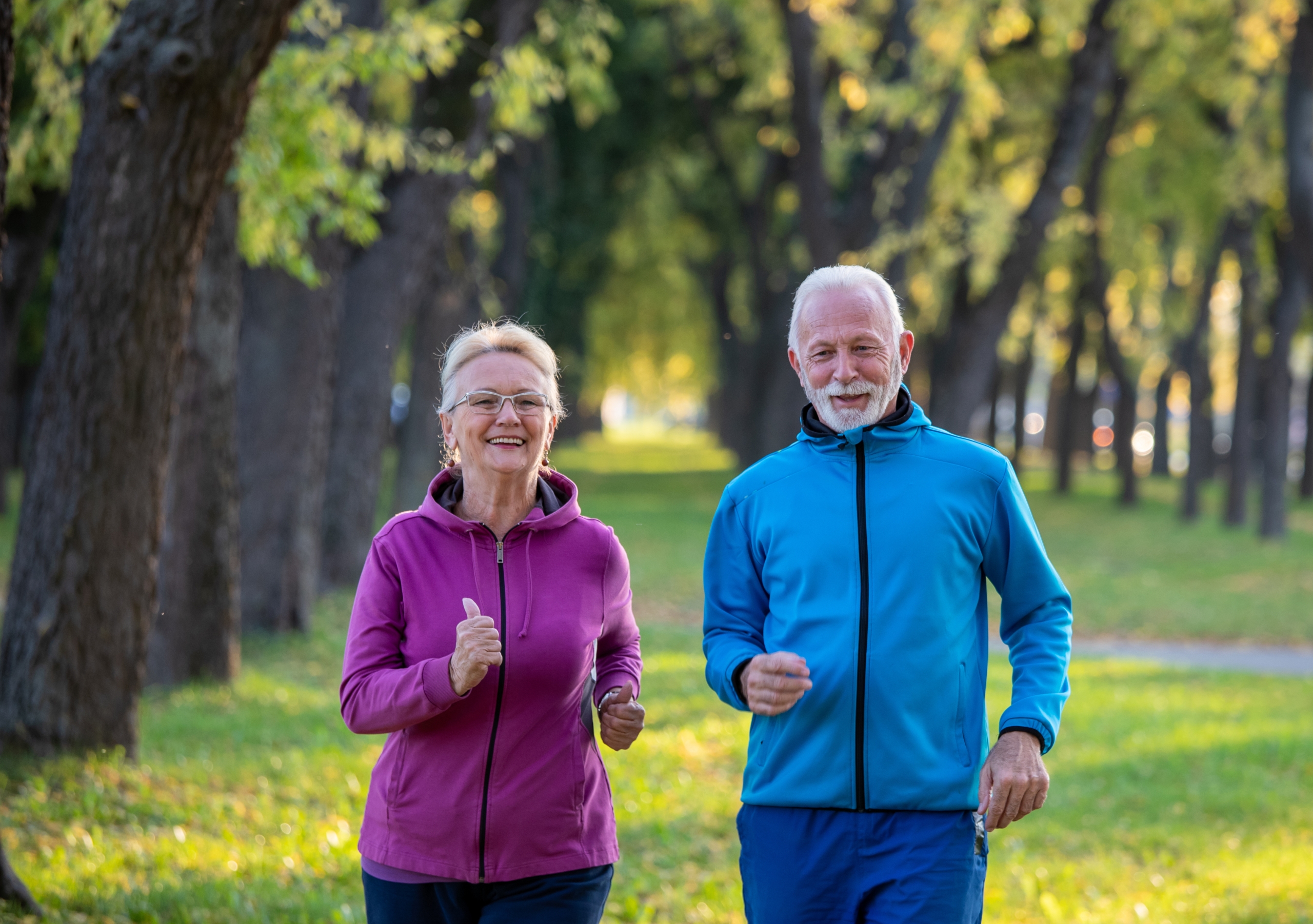 Older couple jogging in park.